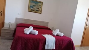 A hotel room with a bed, a nightstand, a painting on the wall, and a door. - b&b Borgo Pileri (Mazzarino)