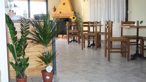 A dining area with wooden chairs and tables, a brick fireplace, and potted plants. - b&b Borgo Pileri (Mazzarino)