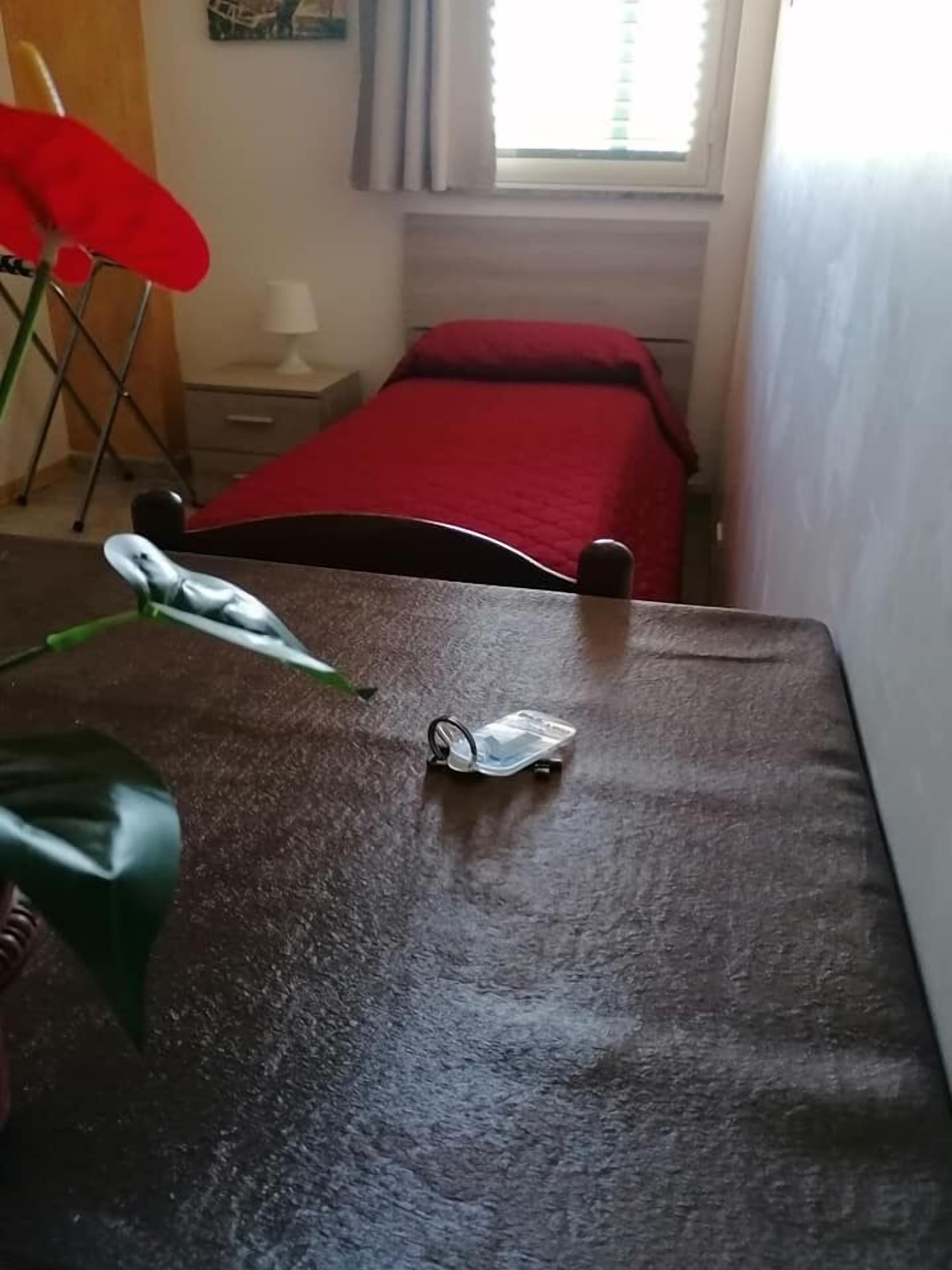 A room with a bed, a small table, and a window with curtains.