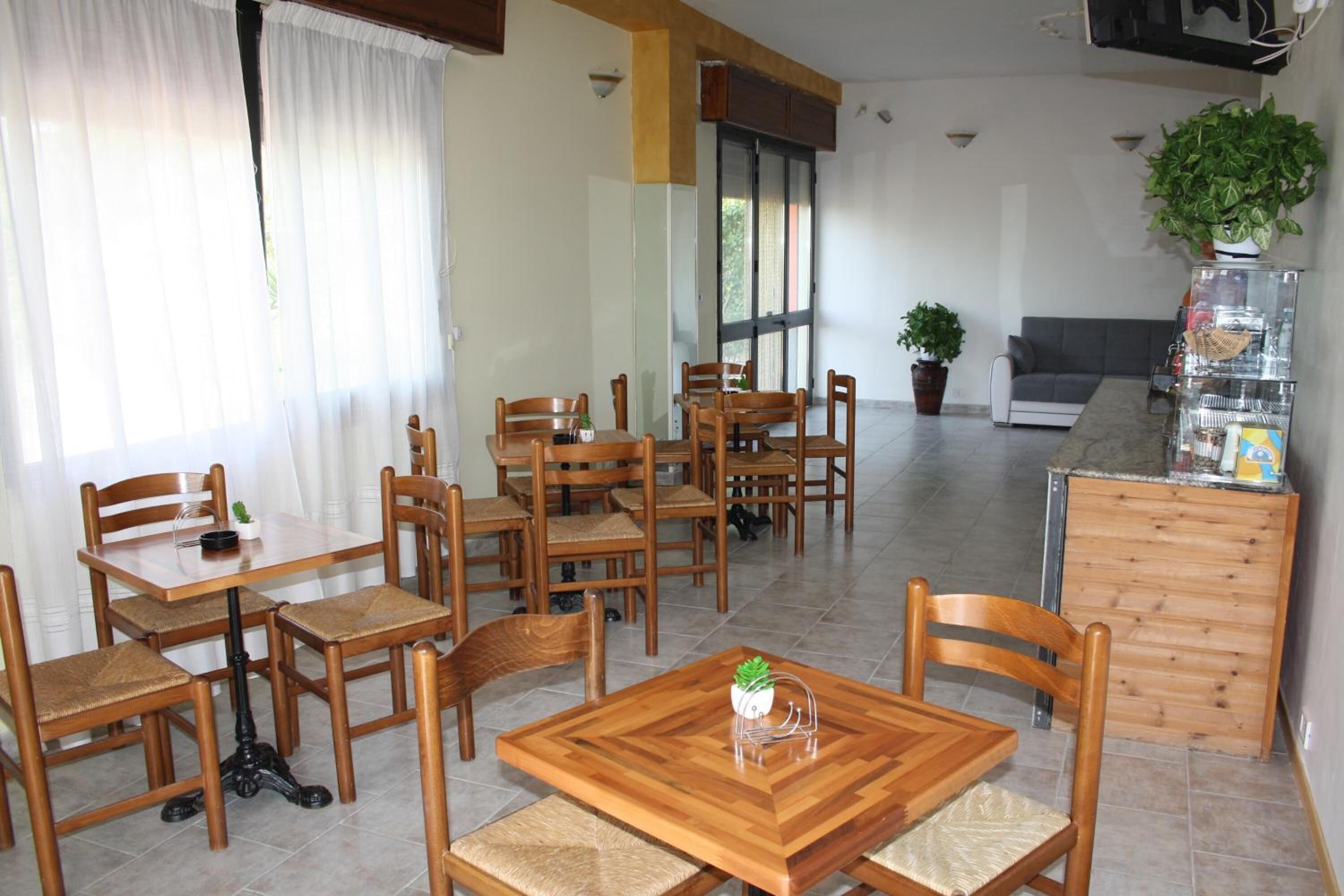 A dining area with wooden tables and chairs, a sofa, and a potted plant.