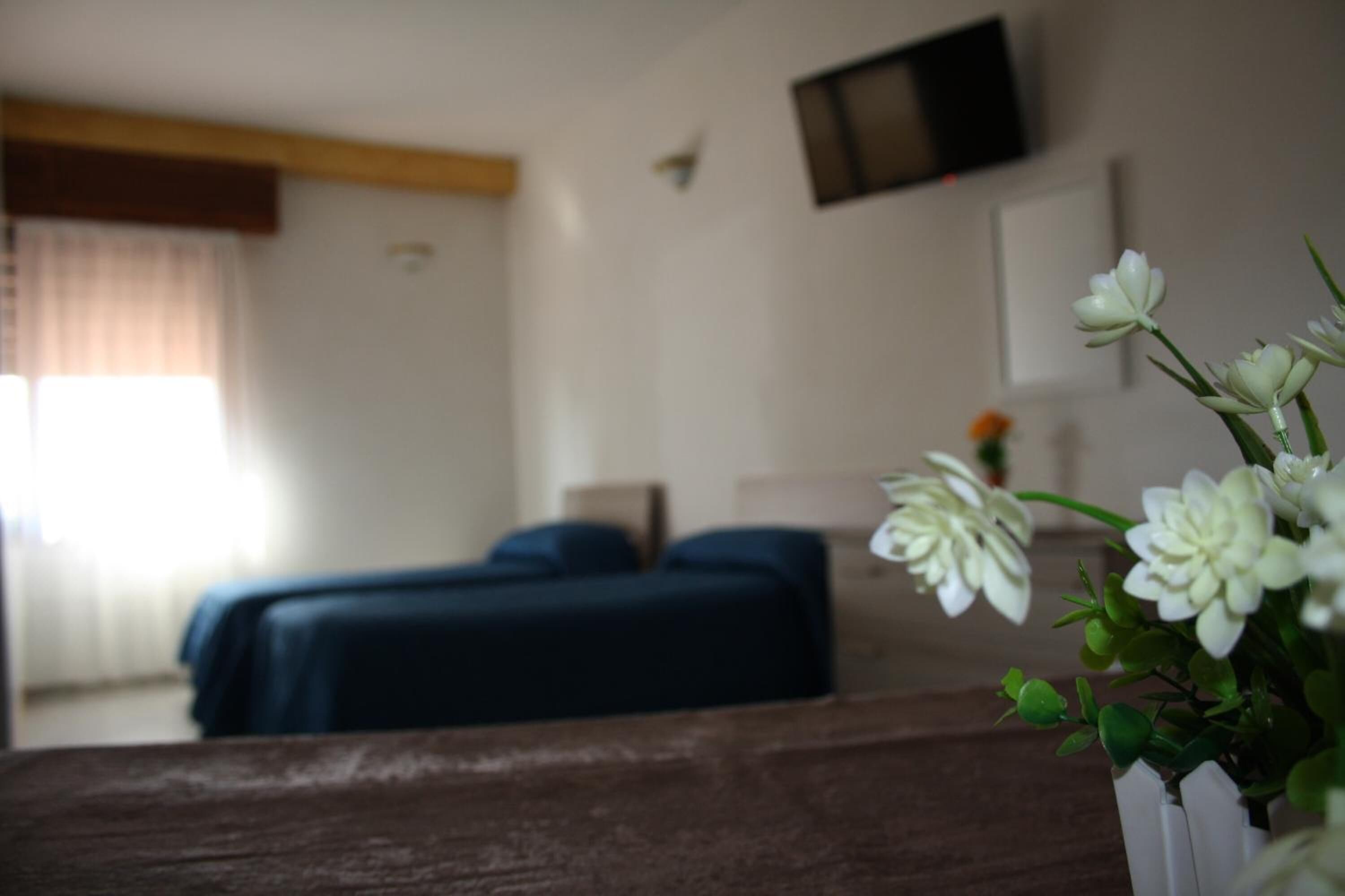 A hotel room with a bed, a TV mounted on the wall, and a window with curtains.