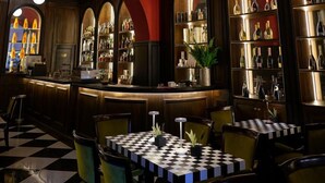 A bar area with a checkered floor, a bar counter, and shelves with bottles. - Il Campo Marzio (Rome)