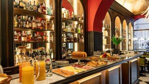 A bar area with shelves of liquor bottles, a buffet with various food items, and a coffee station. - Il Campo Marzio (Rome)