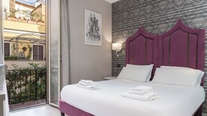 A hotel room with a bed, a view of the outside balcony, a cityscape painting, and a patterned wall. - Il Campo Marzio (Rome)