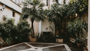 A courtyard with potted plants, a stone fountain, and a tiled floor. - Il Campo Marzio (Rome)