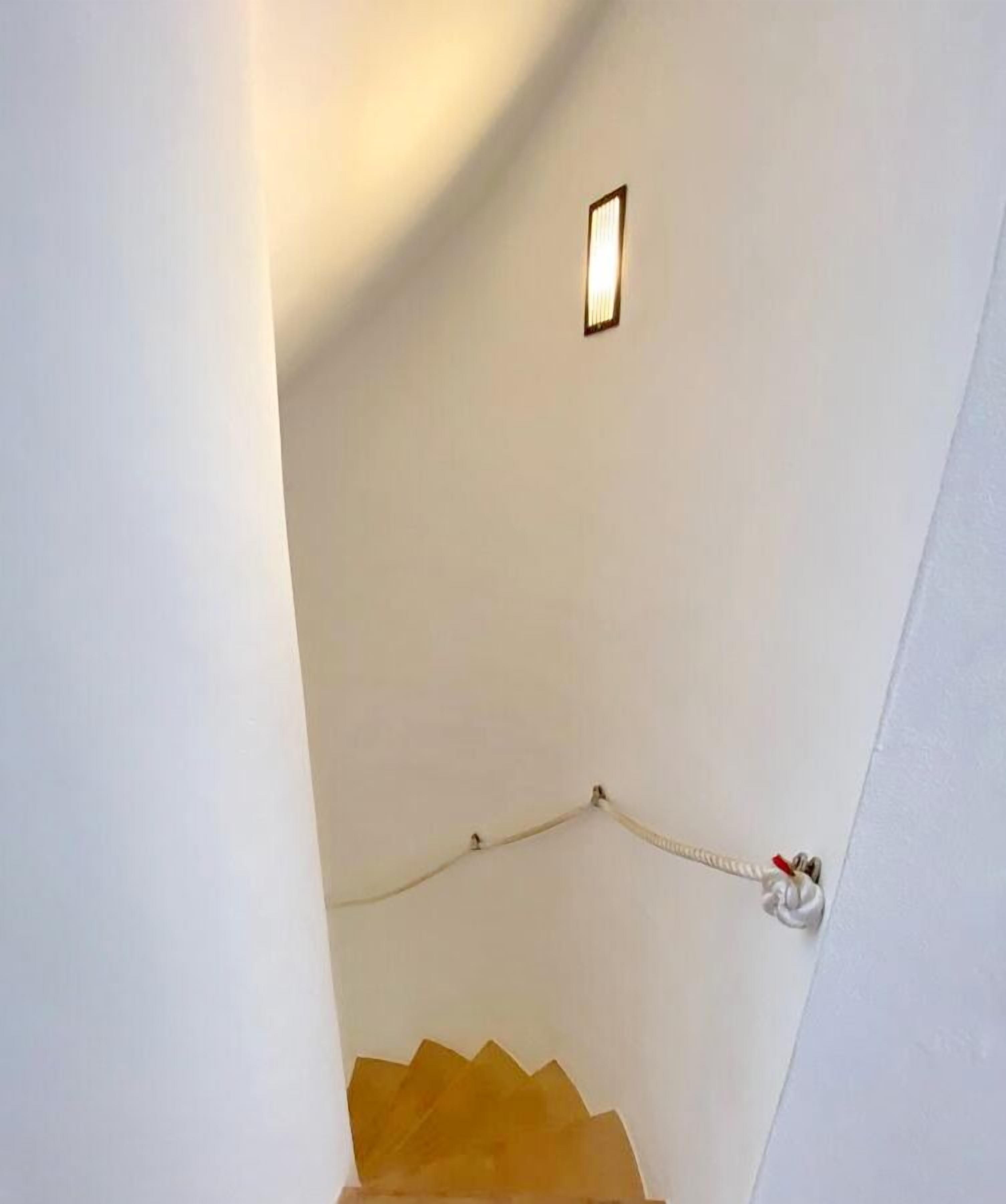 Eine weiße Treppe mit Handlauf und Wandleuchte.