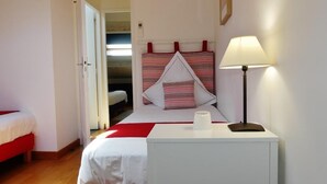 A hotel room with a bed, a bedside table with a lamp, and a red and white patterned headboard.