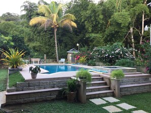 A backyard with a swimming pool, stone steps, and various potted plants. - Garden View (St Joseph)