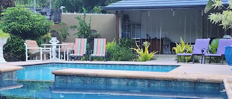 A swimming pool with lounge chairs and a covered seating area.