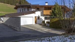 Ein modernes, zweistöckiges Haus mit Garage, geneigtem Dach und einer Holzterrasse.