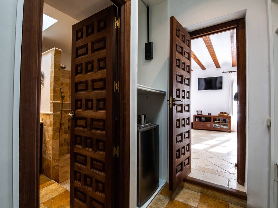 A hallway with a wooden door leading to a bathroom and a living area.