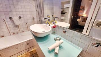 A bathroom with a white sink, a glass countertop, and a mirror. There are towels and toiletries on the counter.