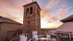 A terrace with outdoor seating, a bell tower, and a view of the city at sunset. - Entre Dos Aguas Hotel Boutique (Toledo)