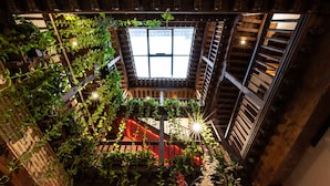 A multi-level atrium with wooden beams, a skylight, and lush greenery. - Entre Dos Aguas Hotel Boutique (Toledo)
