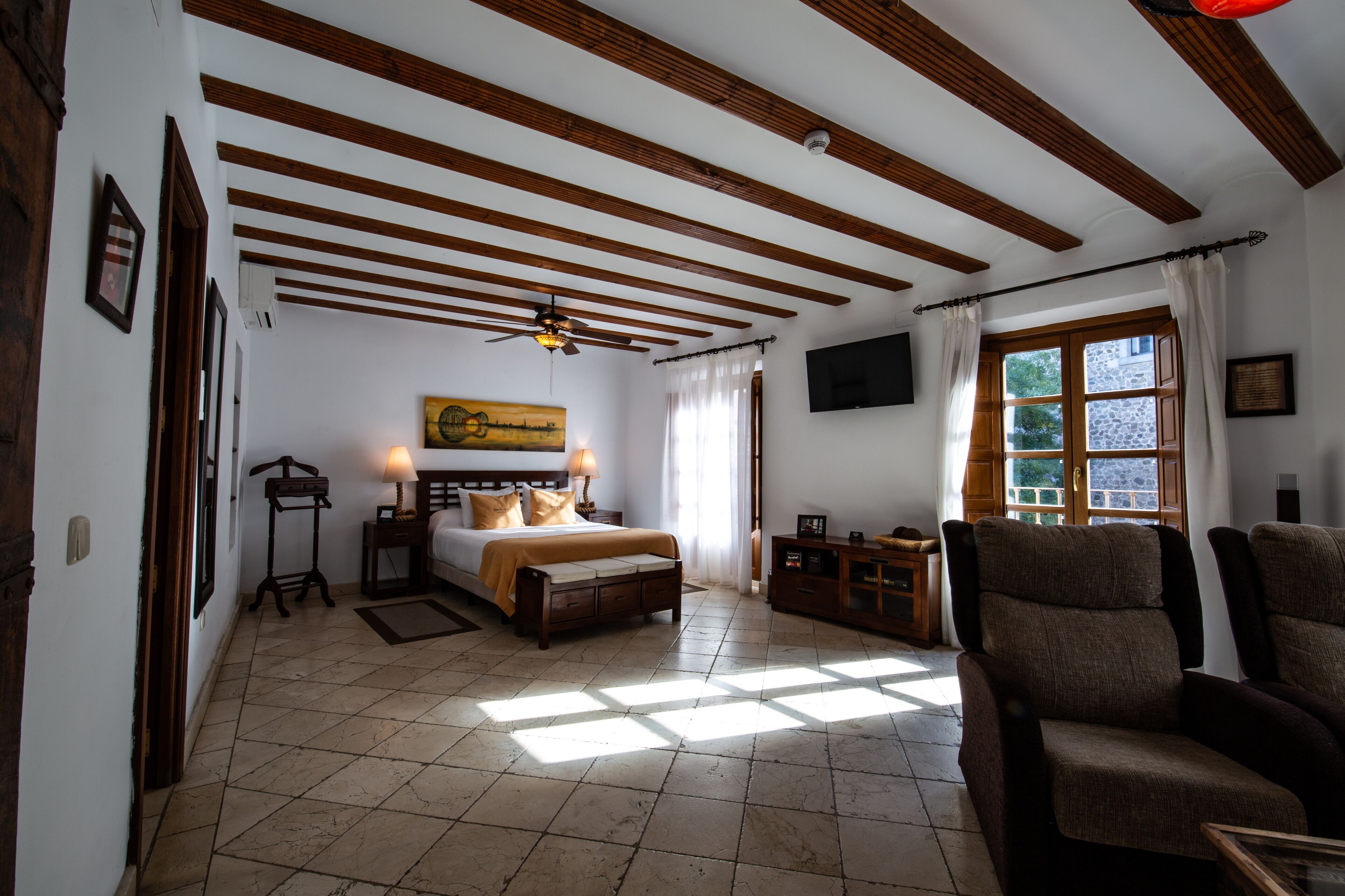 A bedroom with a bed, bedside tables, a TV, and a window with curtains.