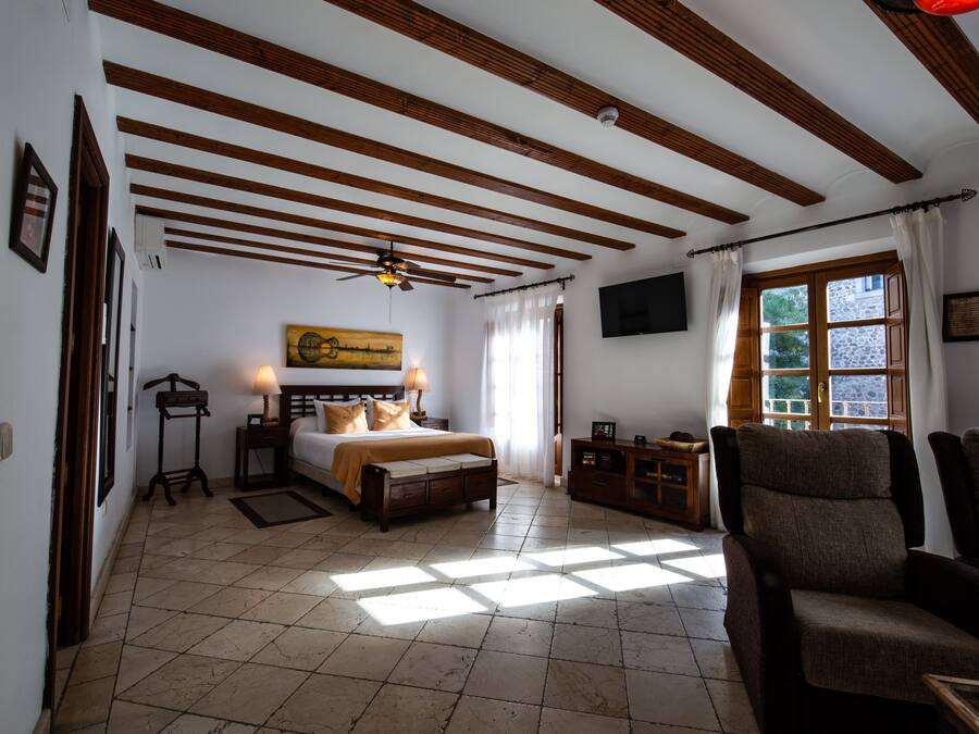 A bedroom with a bed, bedside tables, a TV, and a window with curtains.