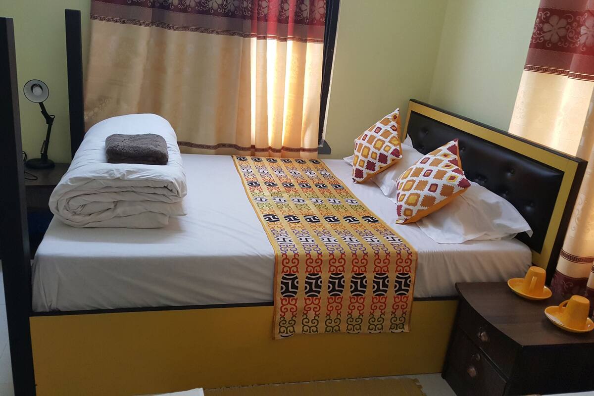 Ein ordentlich bezogenes Bett mit einem gefalteten Handtuch, einer dekorativen Tagesdecke und gemusterten Kissen.