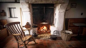Une pièce chaleureuse avec une cheminée, un fauteuil à bascule, une table et un panier.