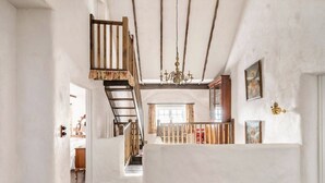 Un intérieur spacieux avec un escalier en bois, un lustre et une vue sur un balcon.