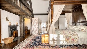 Une chambre à coucher avec un lit à baldaquin, une cheminée et un grand tapis à motifs floraux.