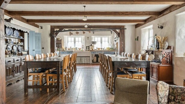 Une cuisine rustique avec des poutres en bois, une longue table à manger et des chaises.