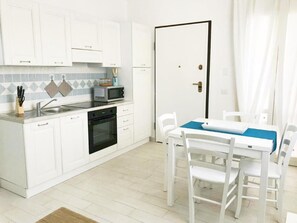 Compact kitchen with microwave and oven, adjacent to a dining area with a table and chairs.