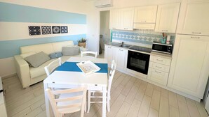 Ett kompakt bostadsutrymme med ett litet kök, en matplats och en soffa.