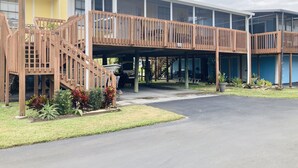 A multi-story building with a covered parking area, wooden staircases, and a sign indicating room number 402. - Water View Villa-monthly rate discount (EVERGLADES CITY)