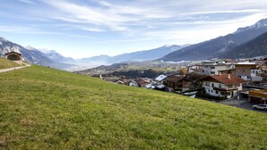A hillside view of a small town with houses, a path, and mountains in the background.