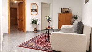 A living room with a sofa, a small table with a vase, a potted plant, and a wooden cabinet.