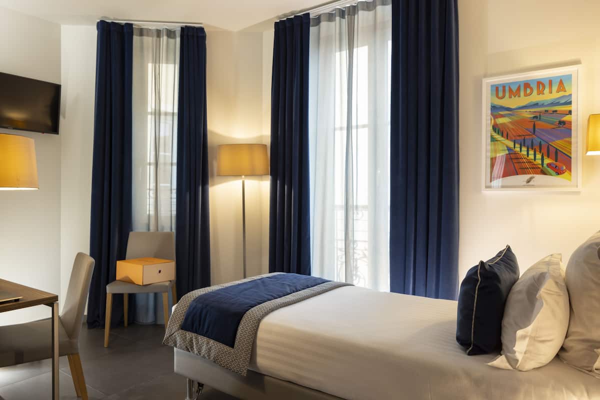 A hotel room with a bed, a desk, a chair, and a TV.