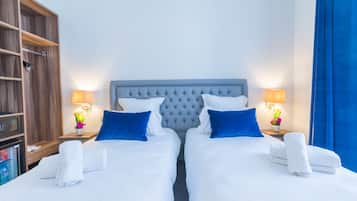 Een hotelkamer met twee bedden, een minibar en een houten garderobe.
