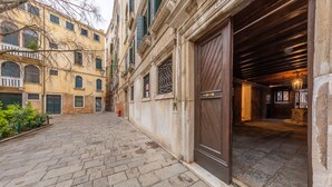 A narrow cobblestone street with historic buildings, a wooden door, and a stone wall. - Loft on two levels exposed beam (Venezia)