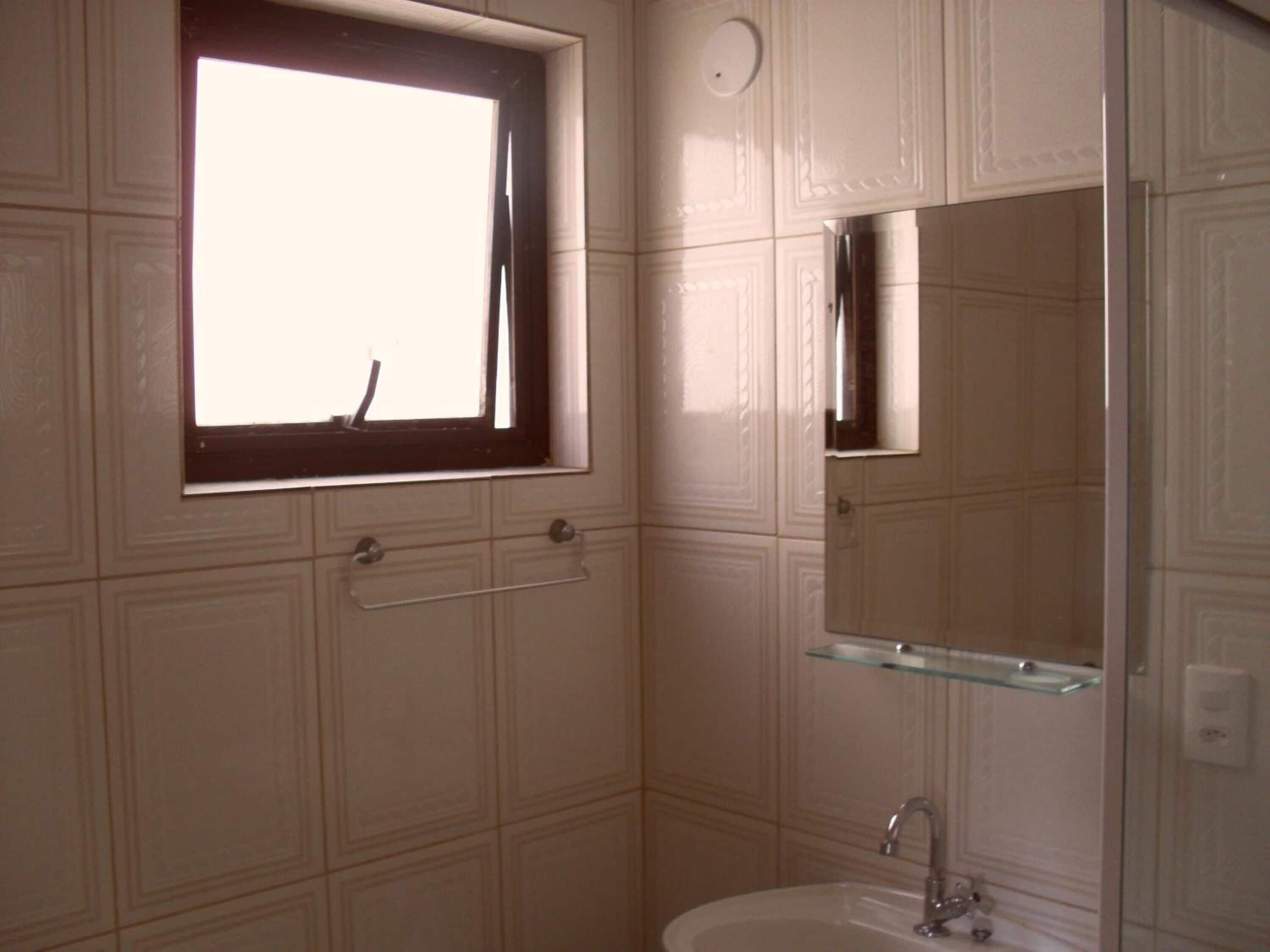 Een badkamer met een raam, een spiegel en een wastafel.
