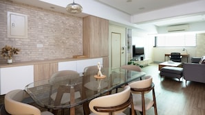 Una cucina moderna con un tavolo da pranzo in vetro, mobili contenitori in legno e illuminazione a sospensione.