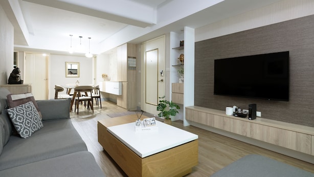 Un soggiorno moderno con una TV a schermo piatto, un tavolino in legno e un divano grigio.