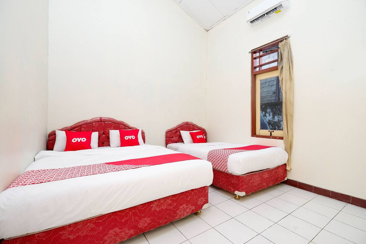 Una habitación con dos camas, cada una con ropa de cama y almohadas a cuadros rojos y blancos.