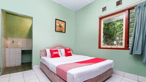 Un dormitorio con cama, ventana con vista a árboles, y baño con lavamanos y espejo.