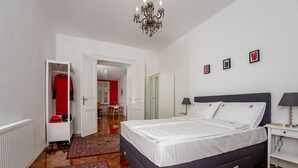 A bedroom with a bed, a wardrobe, a chandelier, and a red wall. - Crown Apartment (Zagreb)