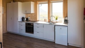 Une cuisine compacte avec des meubles blancs, un lave-vaisselle et une fenêtre donnant sur l’extérieur.