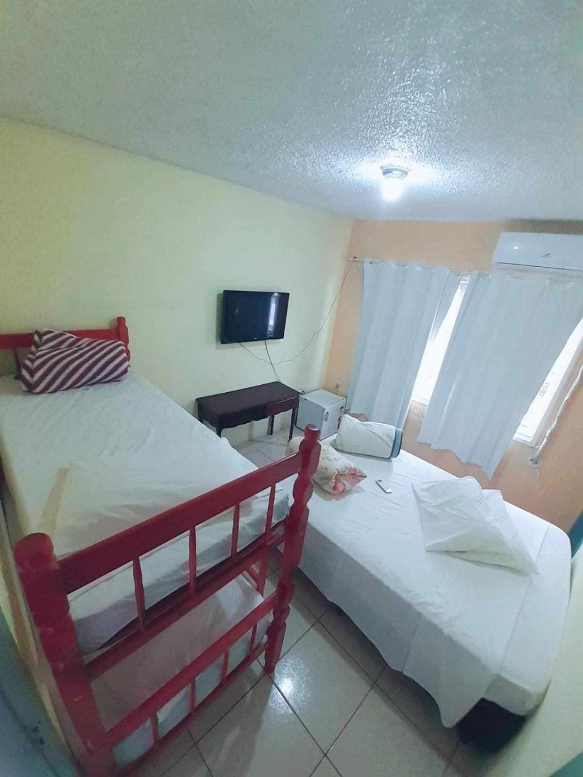 A room with two beds, a television, and a window with curtains.