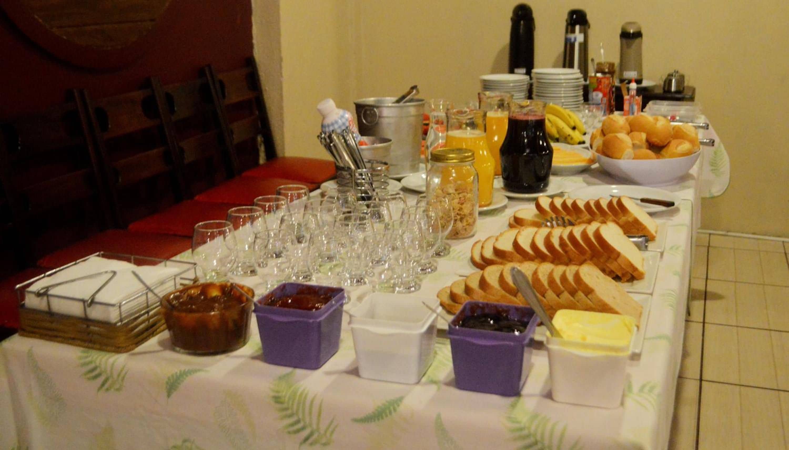 A buffet table with various food items, drinks, and utensils.