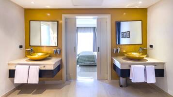 A modern bathroom with two large yellow sinks, mirrors, and a view into a bedroom.