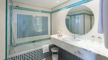 Un bany modern amb dutxa trencada per vidre, un lavabo de marbre i rajoles amb disseny.