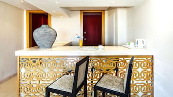 A reception area with a marble counter, two chairs, a vase, and a coffee station.