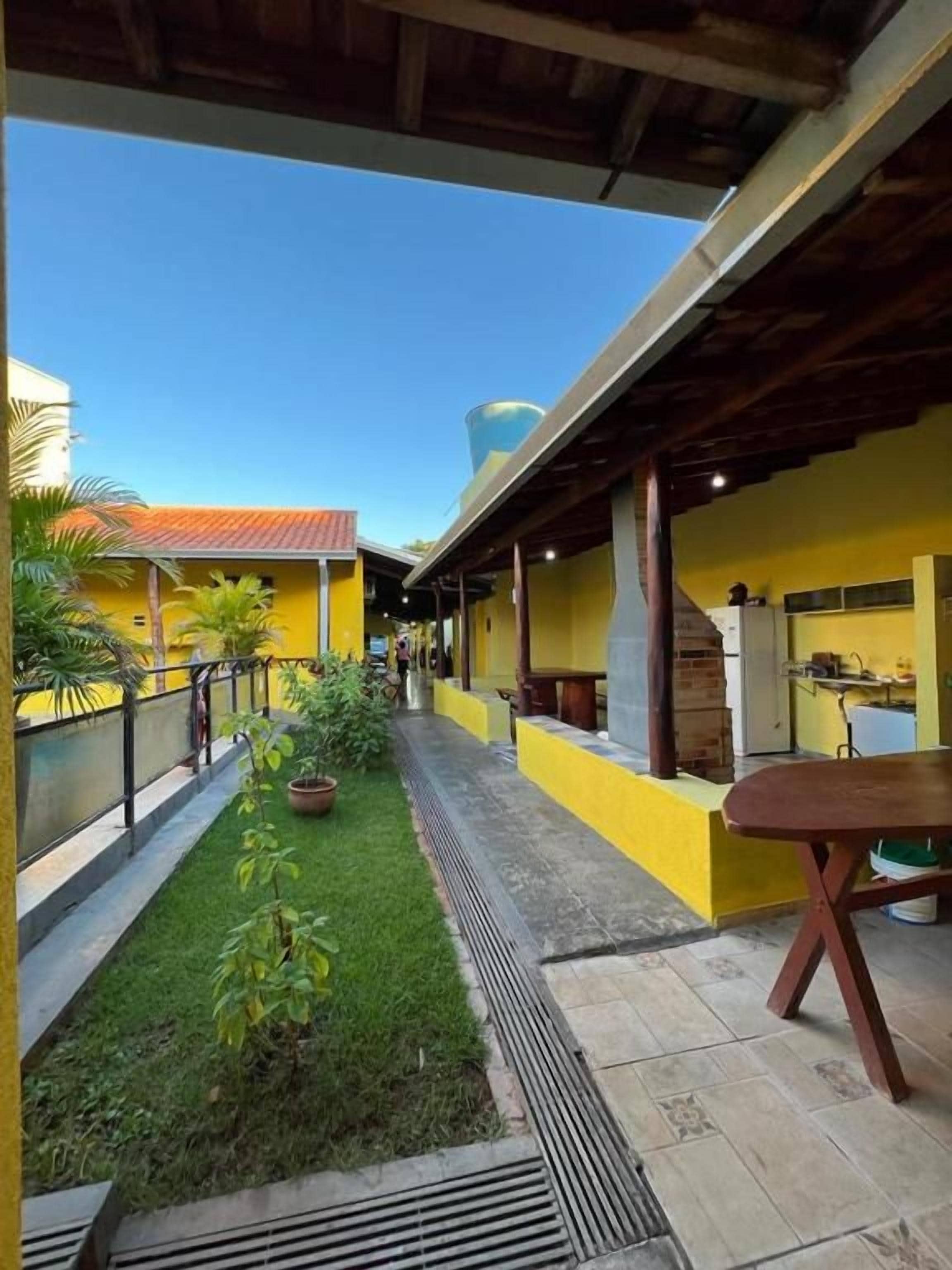 A covered outdoor area with a grassy path, yellow walls, and a table.