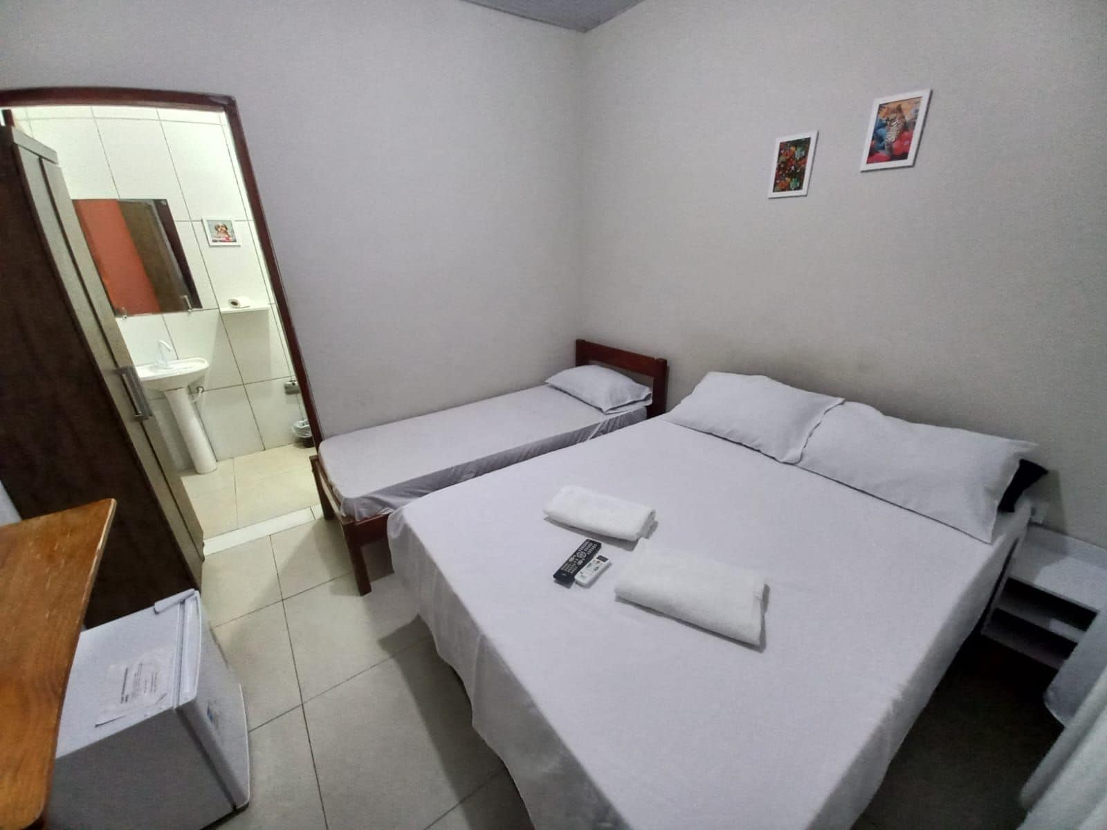 Una habitación de hotel con dos camas individuales, un baño con lavamanos y un espejo.