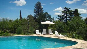 Una piscina al aire libre, sombrillas, sillones reclinables de piscina