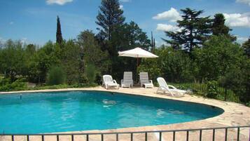 Una piscina al aire libre, sombrillas, sillones reclinables de piscina