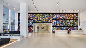 Una hall moderna di un hotel con un'ampia murale astratta, una reception e un'area salotto con un tavolino.